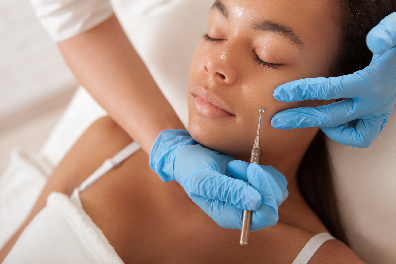 Cosmetologist removing pimples and blackheads on the skin of a beautiful African woman